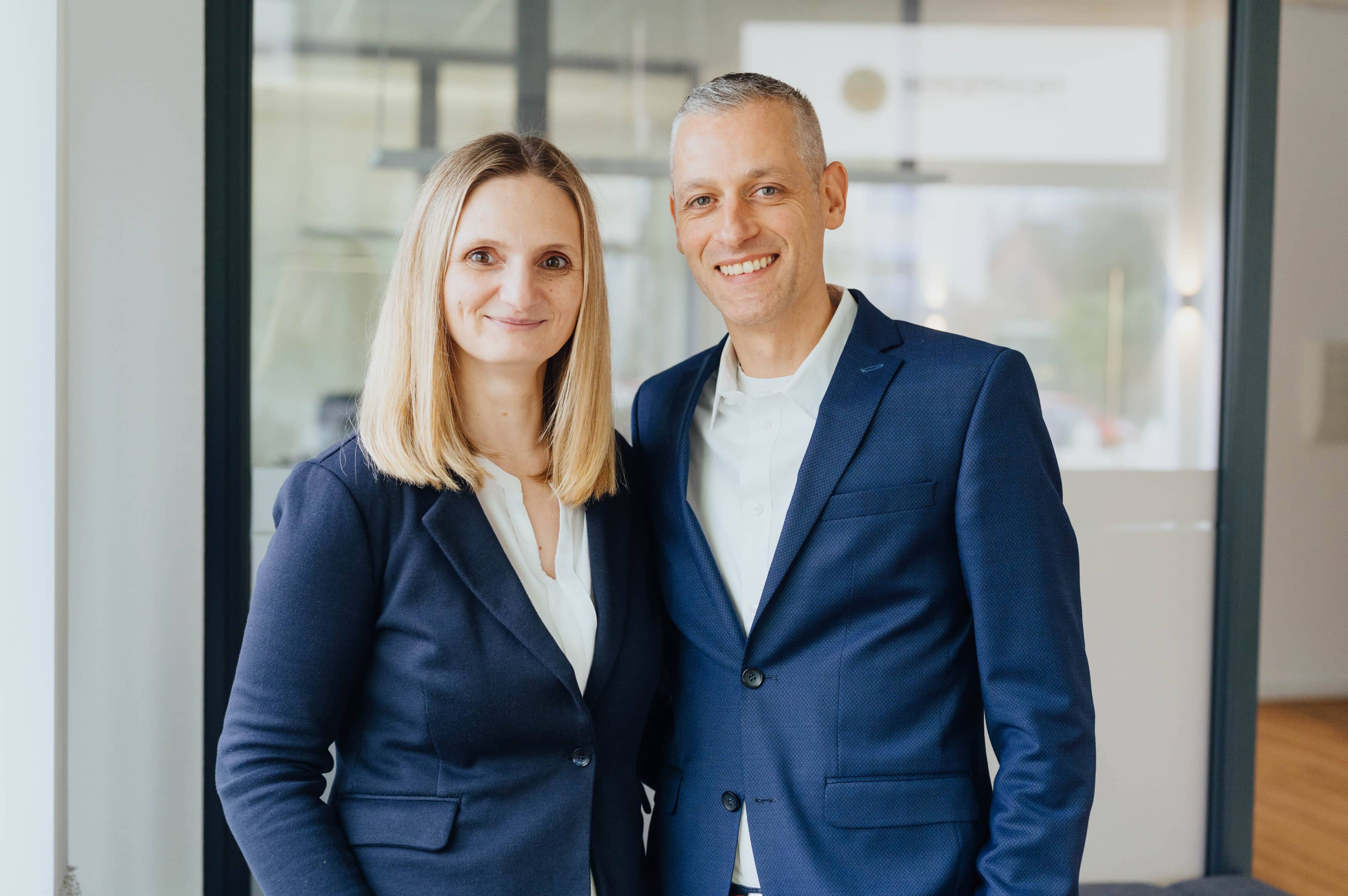 Portraitfoto von Svenja und Karsten Bergerhoff mit lächelnden Mimen in den Büroräumen.